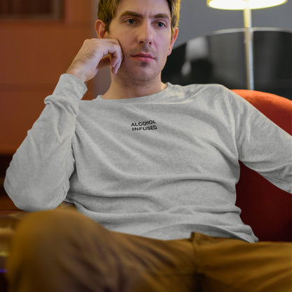 Young man reclines in a red armchair wearing the Alcohol Infused T-shirt, exuding a laid-back vibe amidst a casual indoor setting, embodying unapologetic individuality and subtle rebellion.