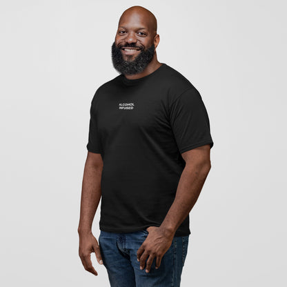 A bearded man models the Alcohol Infused T-shirt, featuring white text on a black tee, embodying a carefree, rebellious spirit. Paired with blue jeans, it echoes a lifestyle of bold, unapologetic expression.