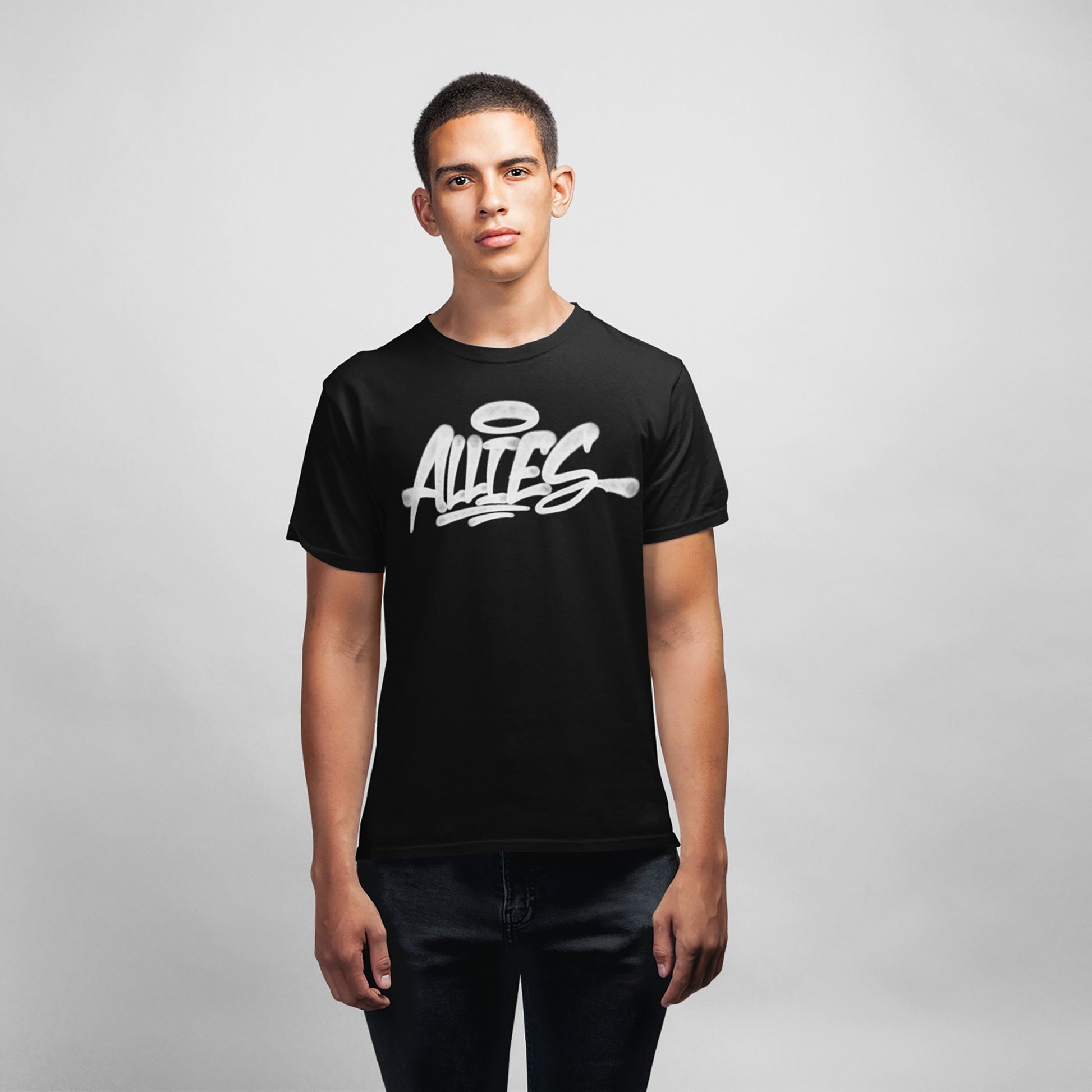 Young man wearing the Allies Handstyle T-shirt, featuring ALLIES in white graffiti-style script with a halo above the A, symbolizing solidarity and allyship, against a neutral background.