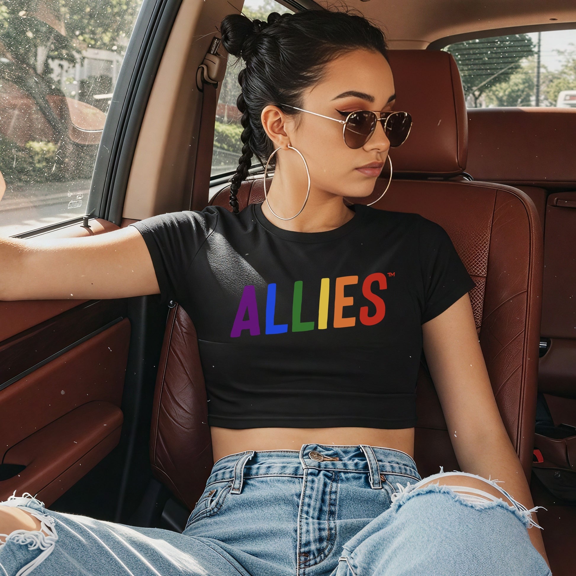 Young person reclines in car wearing Allies Rainbow Women's Baby Tee, displaying bold ALLIES in rainbow colors. The cropped tee embraces Y2K style, symbolizing unity and allyship with the LGBTQ+ community.