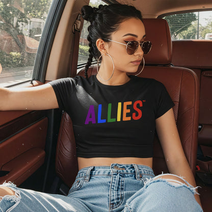 Young person reclines in car wearing Allies Rainbow Women's Baby Tee, displaying bold ALLIES in rainbow colors. The cropped tee embraces Y2K style, symbolizing unity and allyship with the LGBTQ+ community.