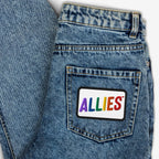 The Allies Rainbow Patch adorns the back pocket of blue denim jeans, featuring vibrant multicolored letters, symbolizing LGBTQ+ support and allyship.