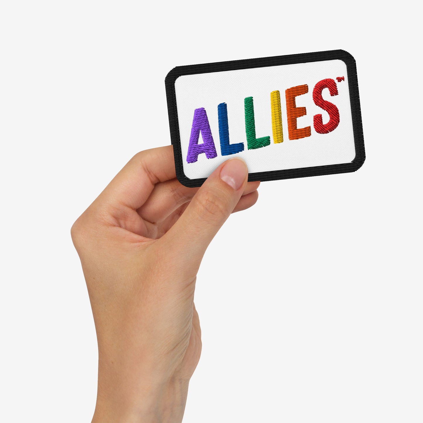 Hand holding Allies Rainbow Patch with ALLIES stitched in rainbow colors on a white background, symbolizing LGBTQ+ support and allyship.