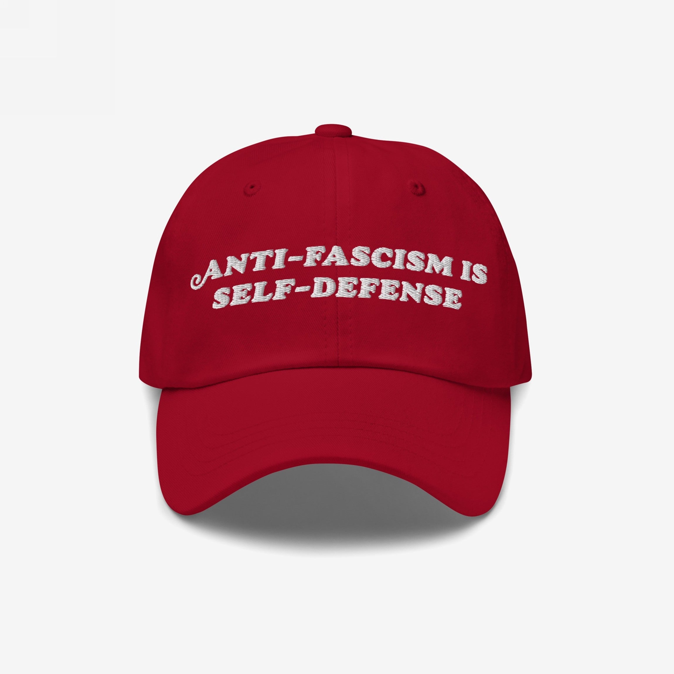Red baseball cap with white embroidered text: ANTI-FASCISM IS SELF-DEFENSE. This Anti Fascism Is Self Defense Hat embodies bold activism, perfect for rallies or everyday resistance, supporting human rights and equality.