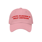 Light-pink Anti Fascism Is Self Defense Hat with bold red embroidery, embodying a retro activist style. Ideal for rallies or 