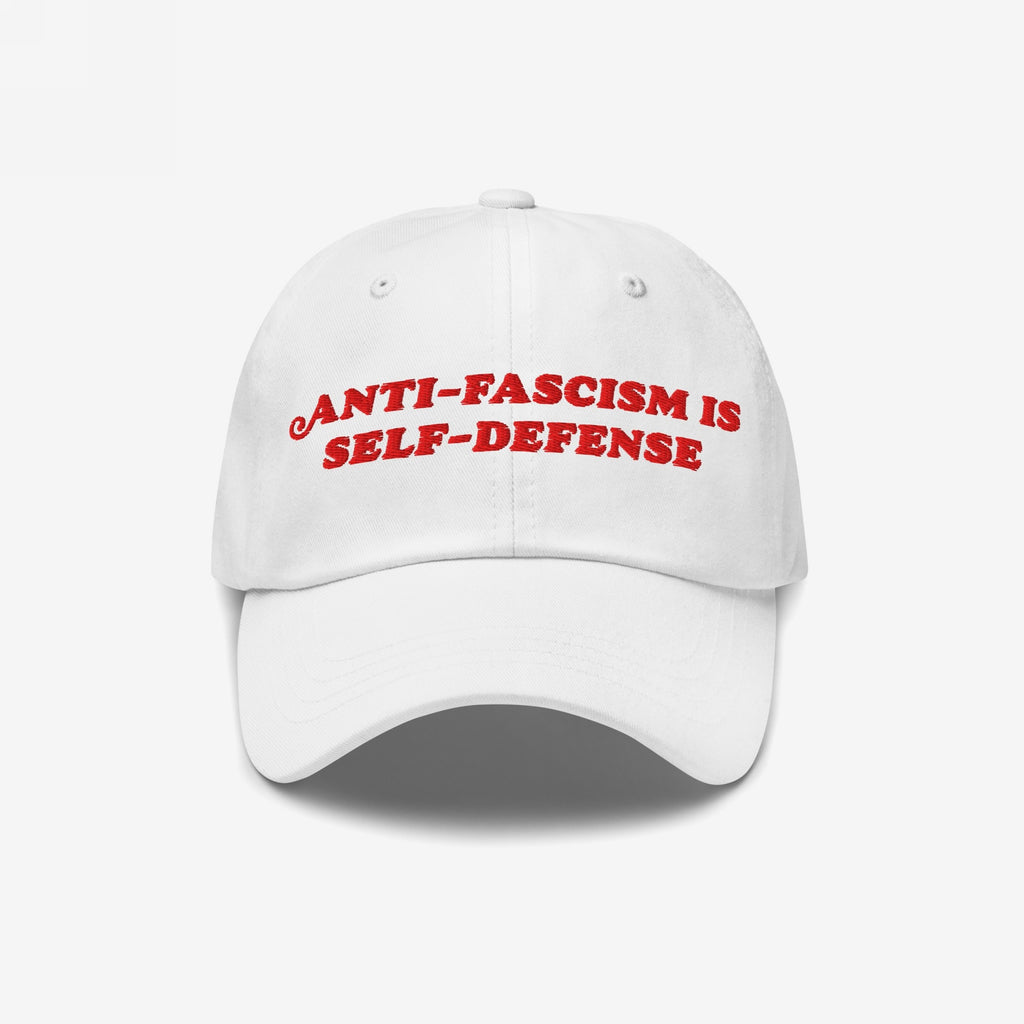 White unstructured baseball cap with bold red embroidery stating “ANTI-FASCISM IS SELF-DEFENSE.” Ideal for activists and allies, this hat supports the ACLU and champions human rights advocacy.