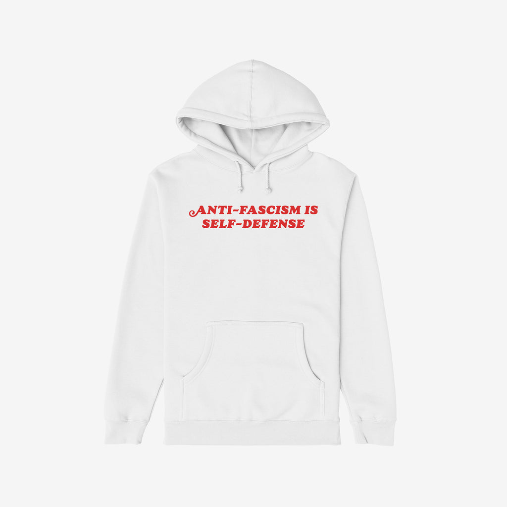 White pullover hoodie featuring ANTI-FASCISM IS SELF-DEFENSE in bold red letters on the chest. This Anti Fascism Is Self Defense Shirt combines vintage style with a strong message supporting equality and justice.