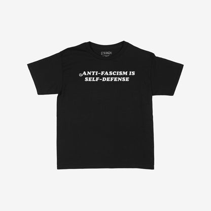 Black T-shirt with bold white serif text, Anti-Fascism Is Self-Defense, highlighting a strong message of resistance and equality. Available in various sizes and styles, embodying a stance against oppression.