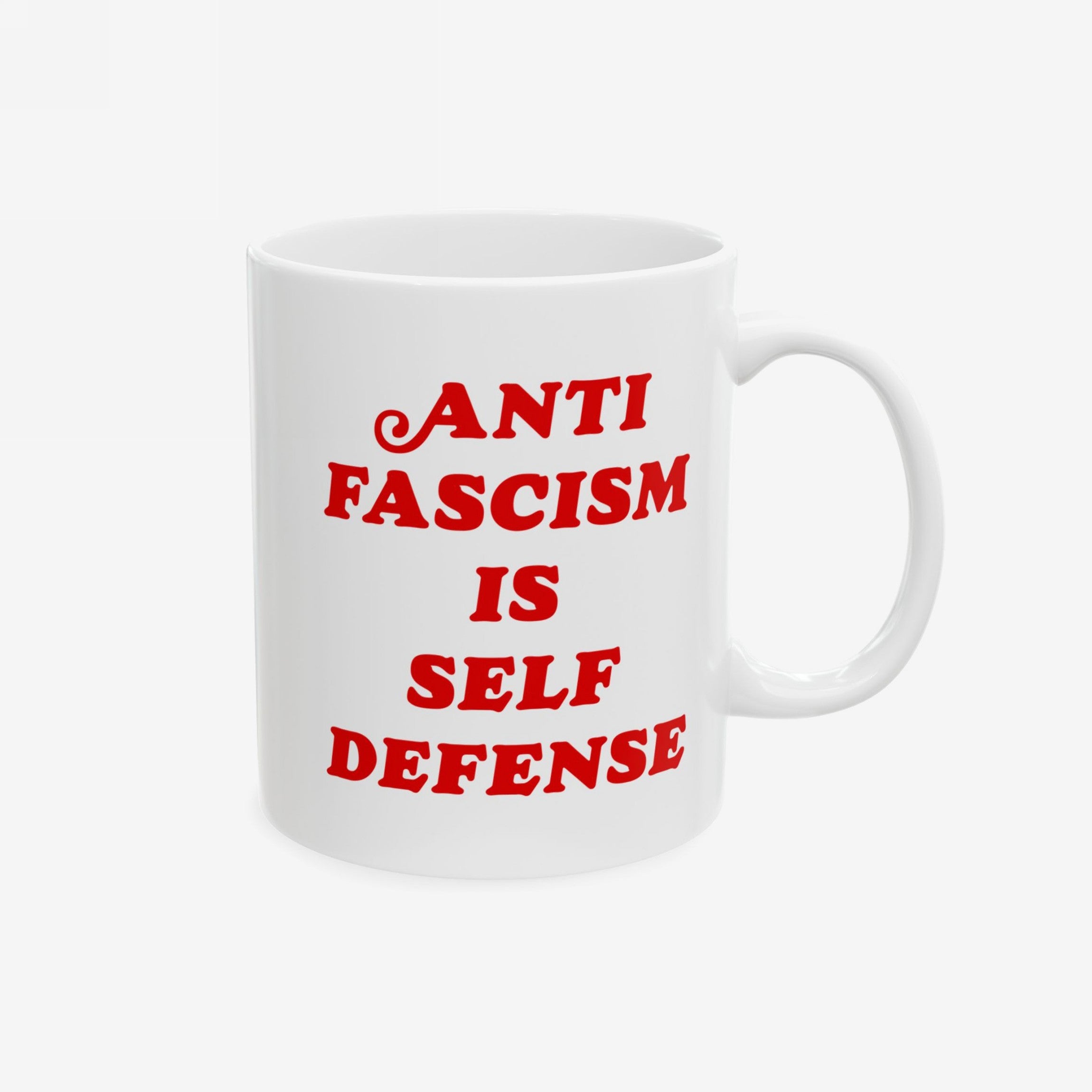 White ceramic mug featuring bold red text, Anti Fascism Is Self Defense, highlighting a powerful message against silence and bigotry. Ideal for progressives, available in 11 oz. and 15 oz. sizes.