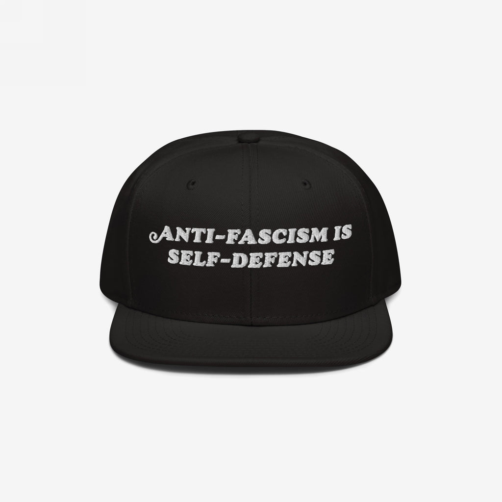 Black snap-back cap with the bold, white embroidered text ANTI-FASCISM IS SELF-DEFENSE, ideal for activists advocating human rights and equality, supporting ACLU.