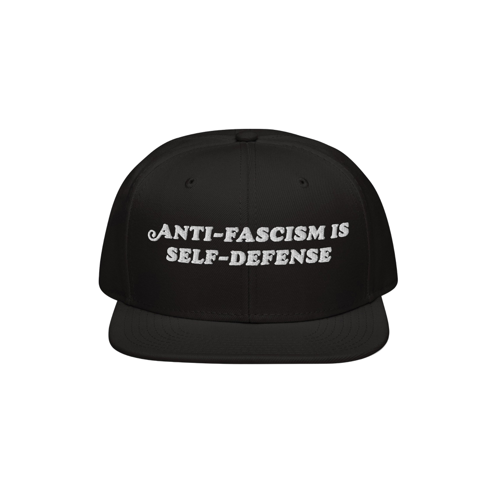 Black snap-back cap with the bold, white embroidered text ANTI-FASCISM IS SELF-DEFENSE, ideal for activists advocating human 