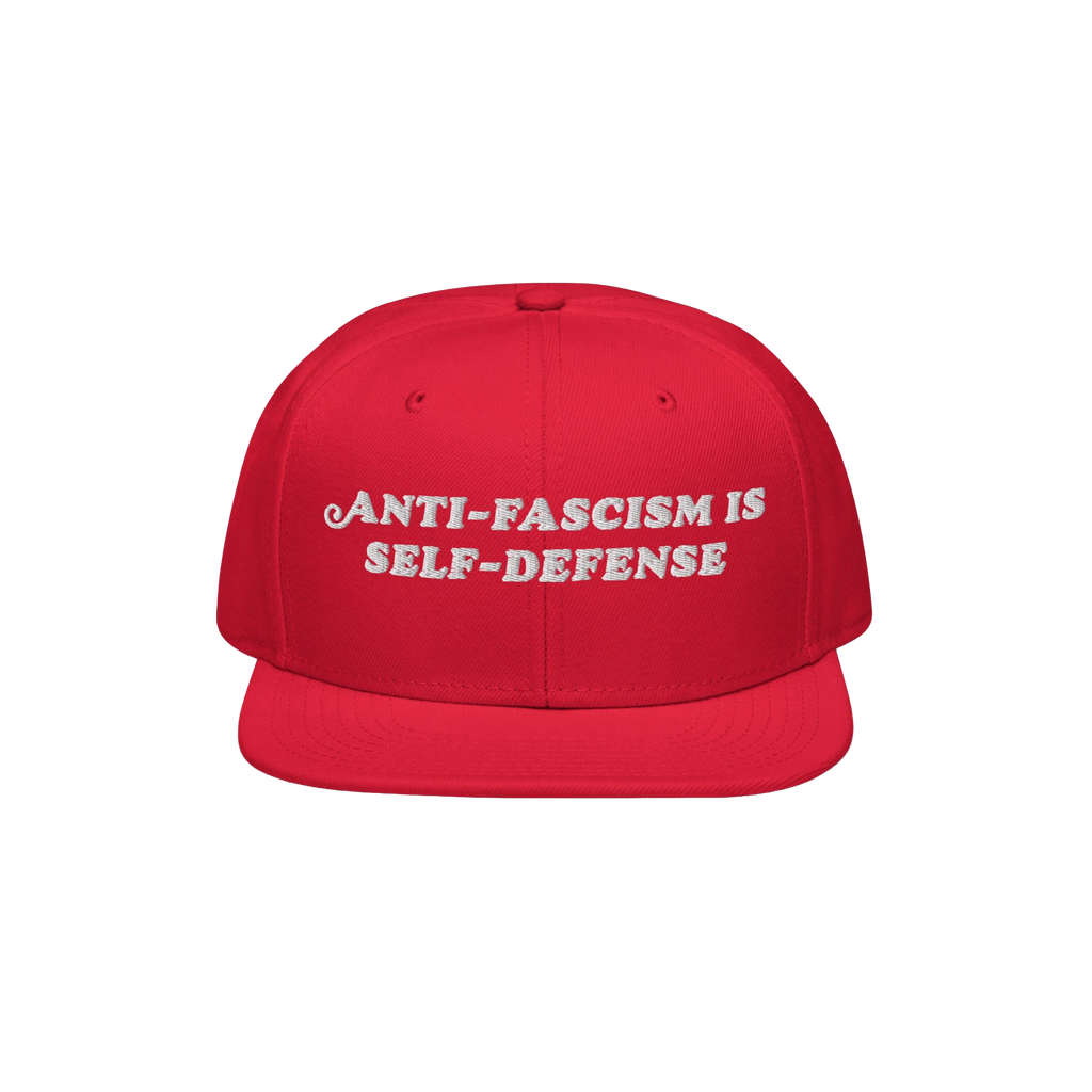 Bright red snapback cap with “ANTI-FASCISM IS SELF-DEFENSE” embroidered in white, embodying activist spirit. Ideal for ra