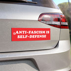 Rear corner of a silver SUV with an Anti-Fascism Is Self-Defense bumper sticker in bold white letters, highlighting a strong stance against fascism.