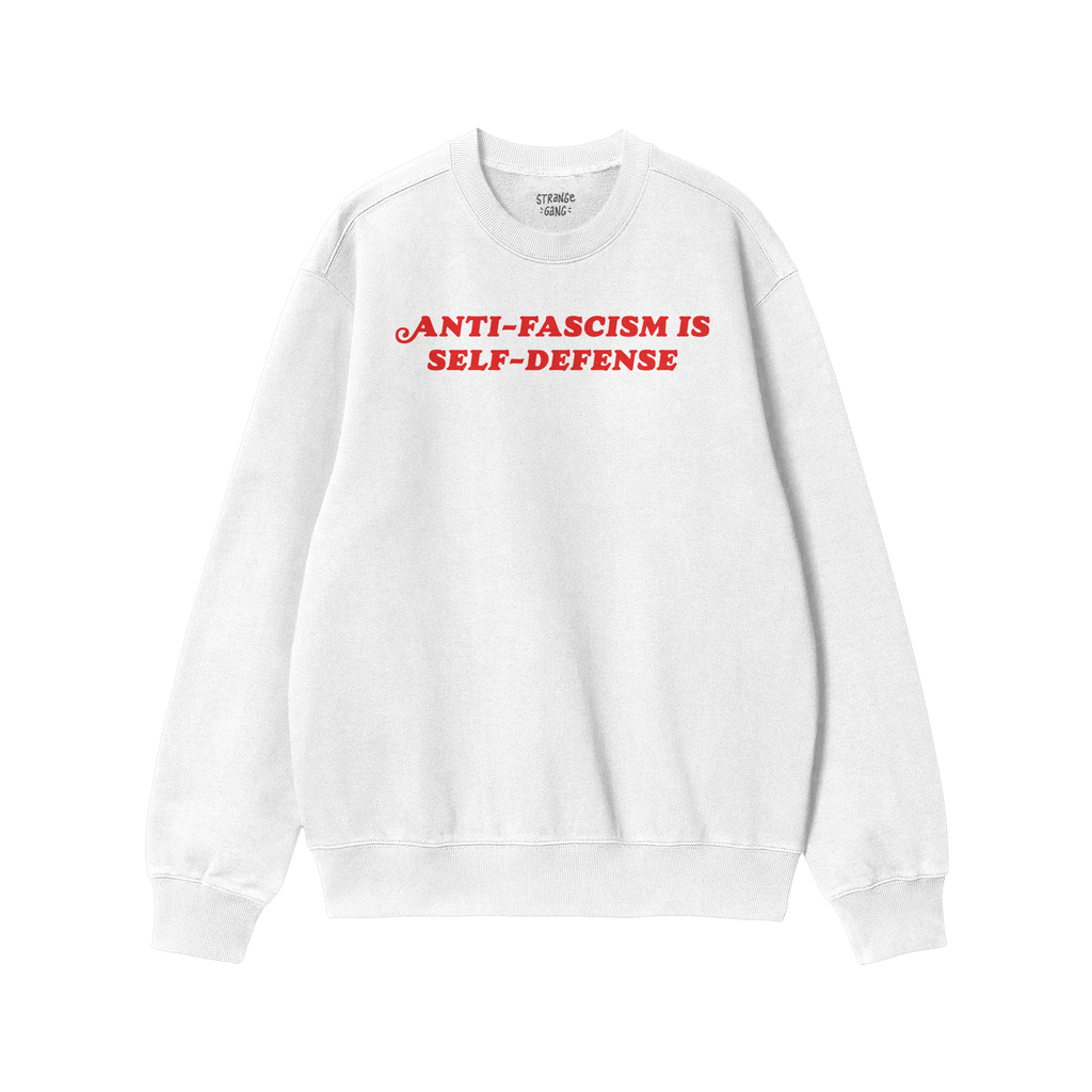 A plain white crewneck sweatshirt with bold red text reading “ANTI-FASCISM IS SELF-DEFENSE,” embodying activism and style