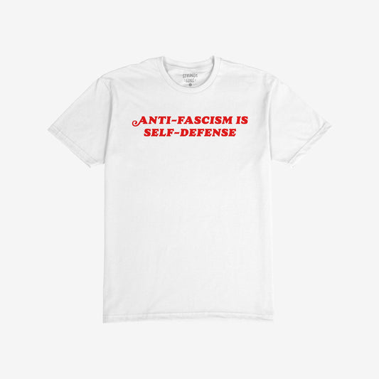 Anti-Fascism Is Self-Defense T-shirt displaying bold red text on a plain white background, emphasizing a strong message of resistance. Label visible inside the collar.