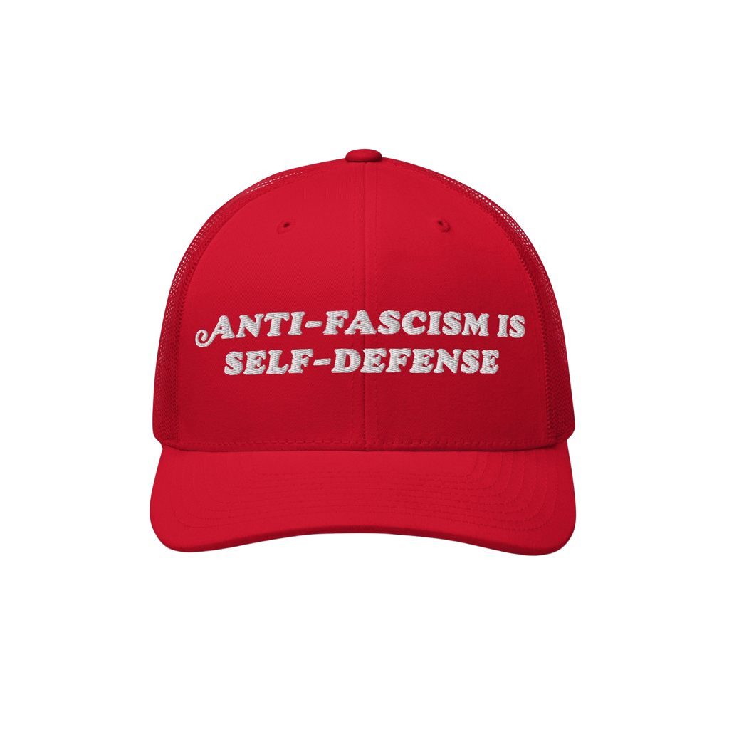 The image features the Anti Fascism Is Self Defense Hat, a red mesh-back trucker cap with ANTI-FASCISM IS SELF-DEFENSE embroi