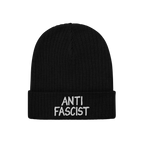 Black rib-knit beanie with ANTI FASCIST embroidered in white on the cuff, symbolizing resistance. Unisex design, ethically cr