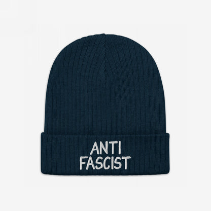 Dark-blue rib-knit beanie with “ANTI FASCIST” embroidered in white on the cuff, embodying protest spirit and ethical fashion.