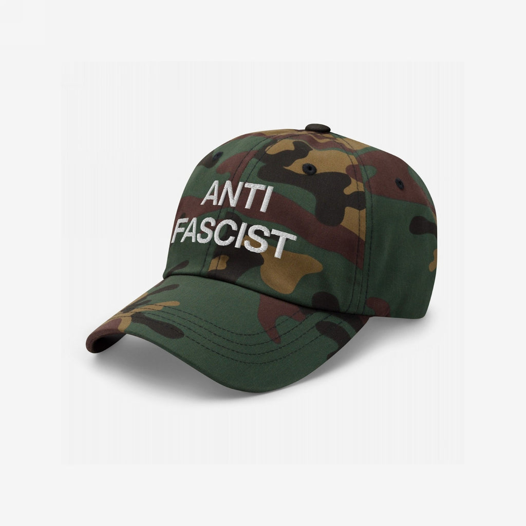 Anti-Fascist Classic Hat with 'ANTI FASCIST' in bold white embroidery, featuring a camouflage design. A statement piece for those committed to resistance and equality, available in various styles.