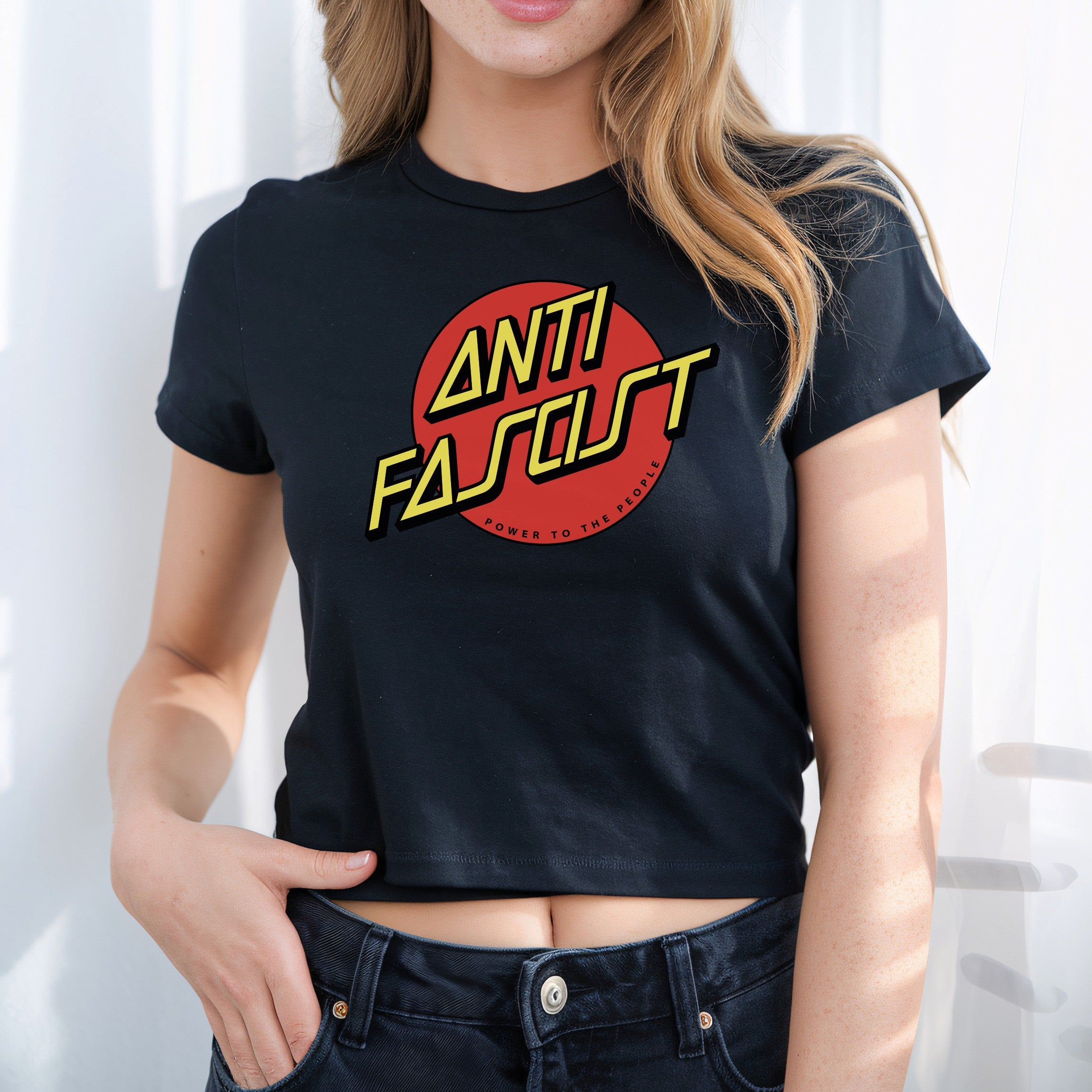 Person wearing the Anti-Fascist Women's Baby Tee, featuring a bold red circle and yellow text ANTI FASCIST with Power to the people, embodying defiant, anti-fascist style.