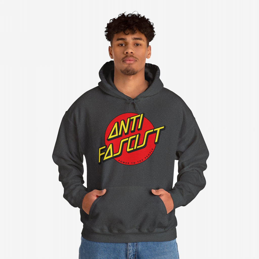 Young man wears an Anti Fascist Hoodie featuring a bold red circle with ANTI FASCIST in yellow lettering, embodying progressive resistance. Ideal for rallies or casual wear, supporting equality and justice.