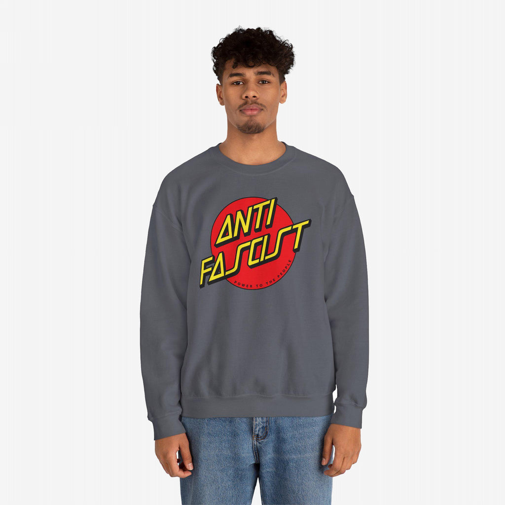 Young man models the Anti Fascist Shirt, featuring a bold red circle with “ANTI FASCIST” in yellow, advocating resistance and equality. He pairs it with medium-wash jeans, embodying progressive street style.