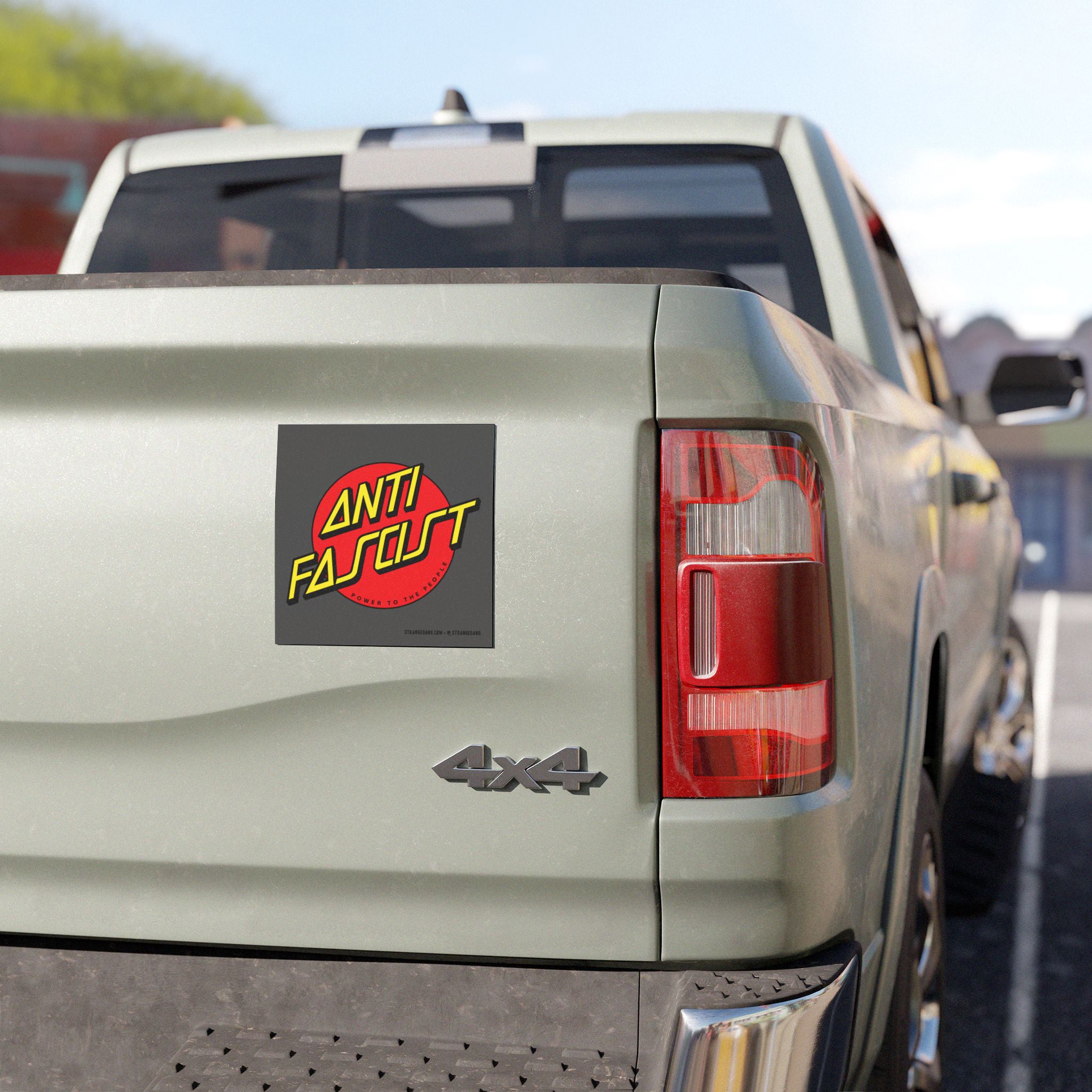 The back of a light-green pickup displays the Anti Fascist Sticker & Magnet, featuring a red circle with bold yellow text and a Power to the People slogan on the tailgate.