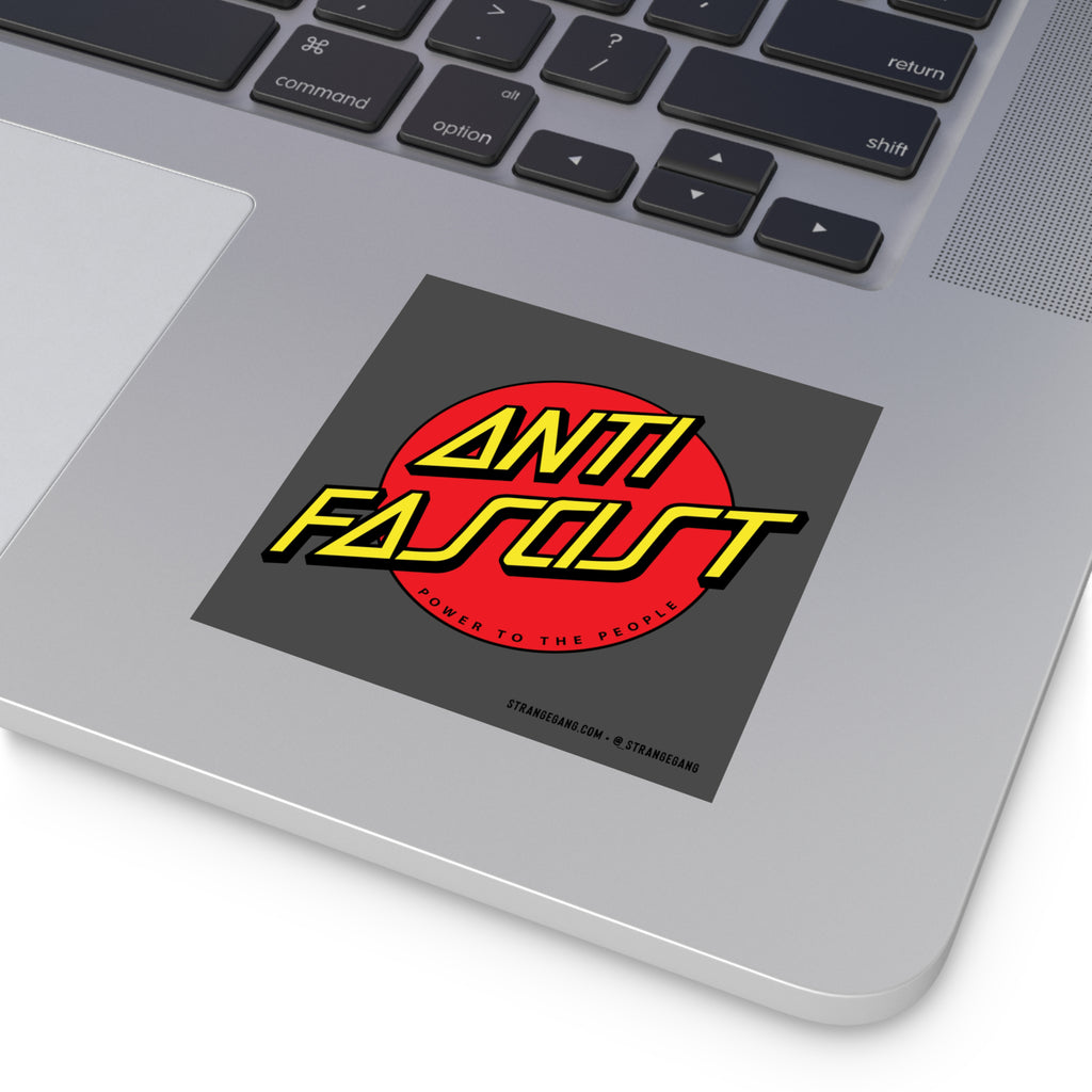 The image shows the palm-rest area of a silver laptop with an Anti Fascist Sticker & Magnet featuring a red circle and bold yellow text promoting progressive values and equality.
