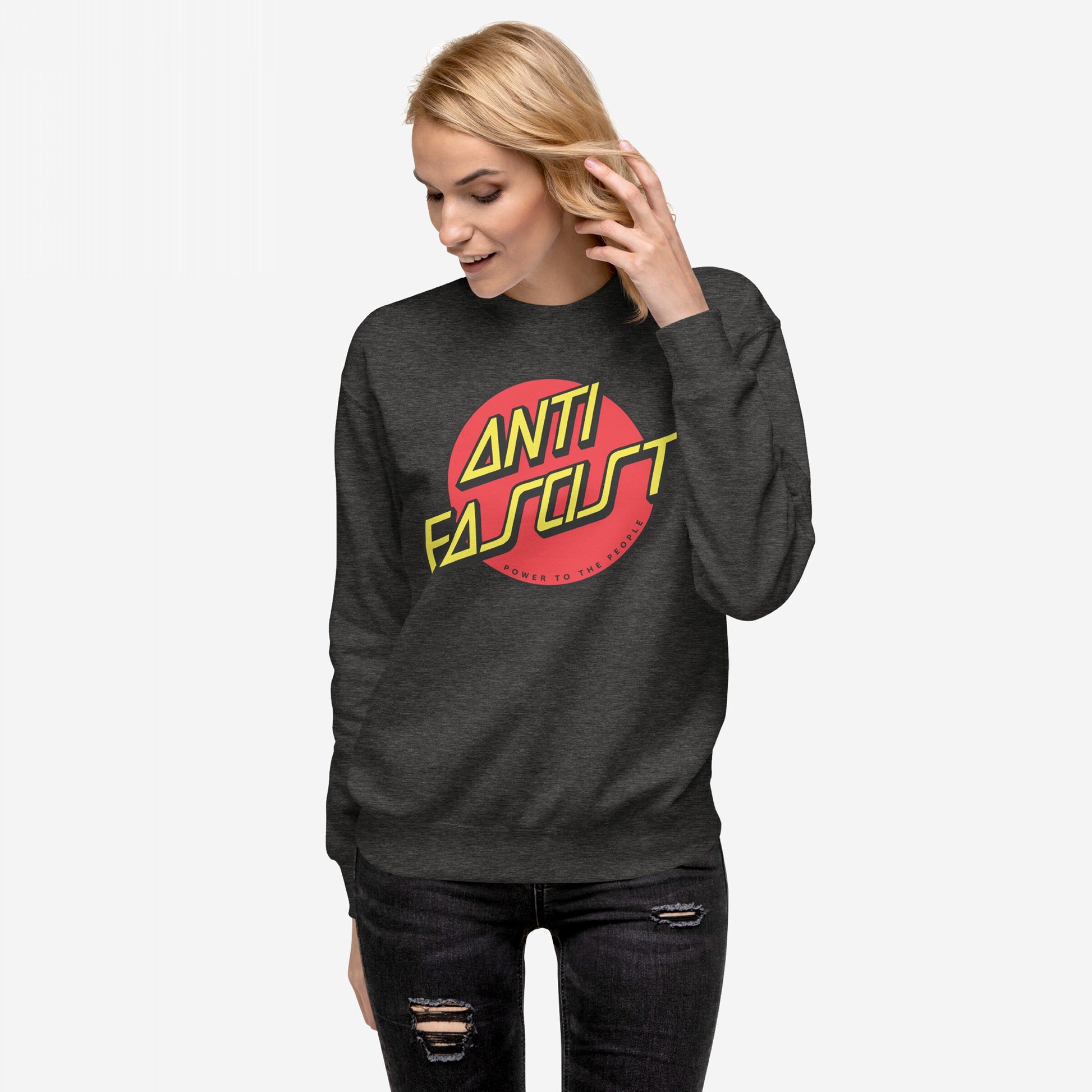 Young woman in a dark gray Anti-Fascist Hoodie & Sweatshirt with ANTI FASCIST and POWER TO THE PEOPLE graphic, embodying skate and street-punk style, wearing black distressed jeans.
