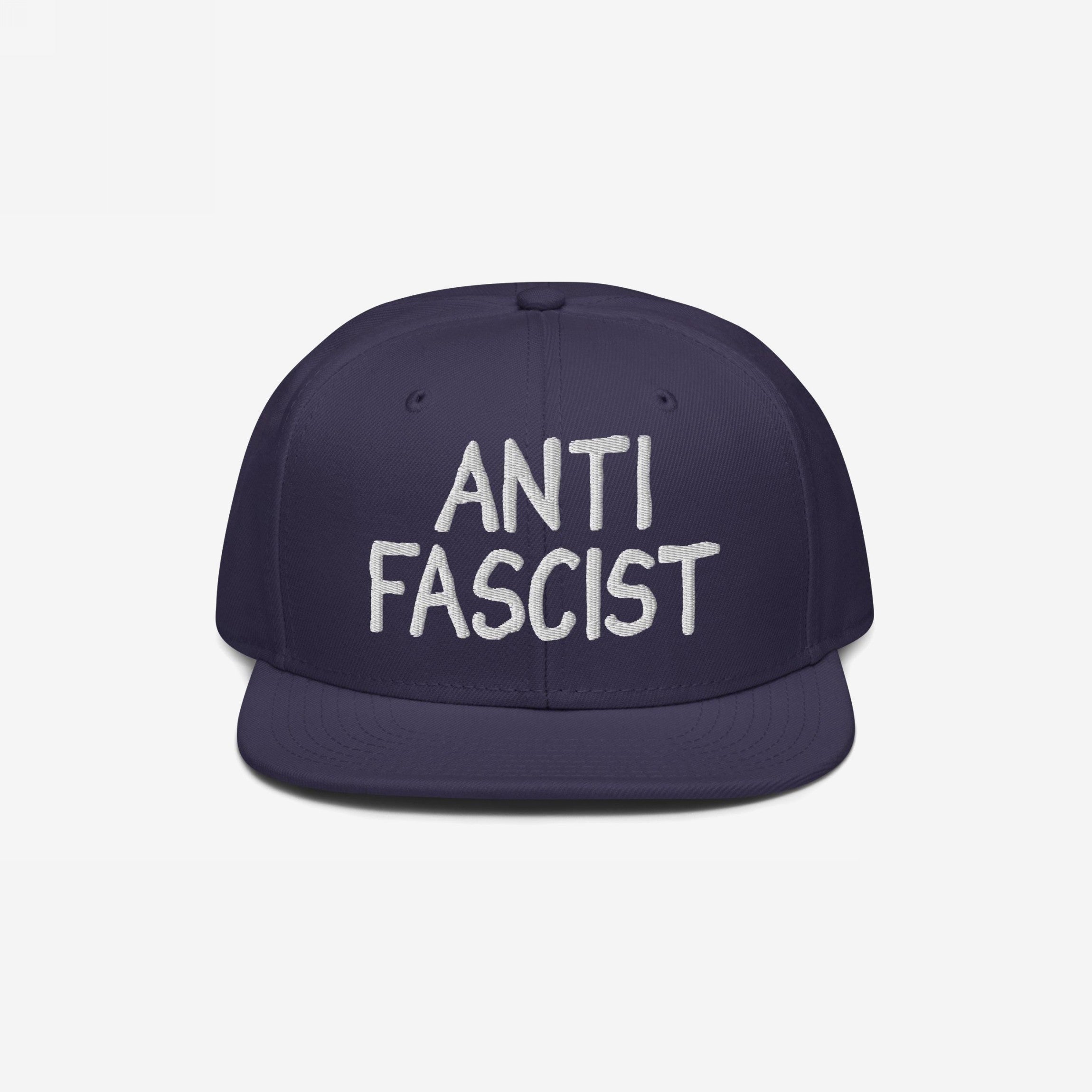 Navy-blue flat-brim snapback hat with ANTI FASCIST in white embroidery, reflecting a bold, unisex statement for those opposing fascism. Ethically made and supports ACLU.