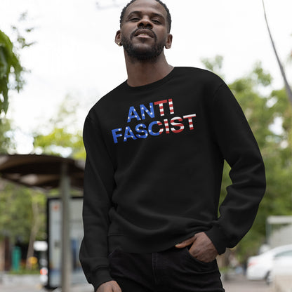 Man outdoors wearing the Anti-Fascist USA Classic Hoodie & Sweatshirt, featuring ANTI FASCIST text with American-flag motif, symbolizing a stand against tyranny and promoting activism and equality.
