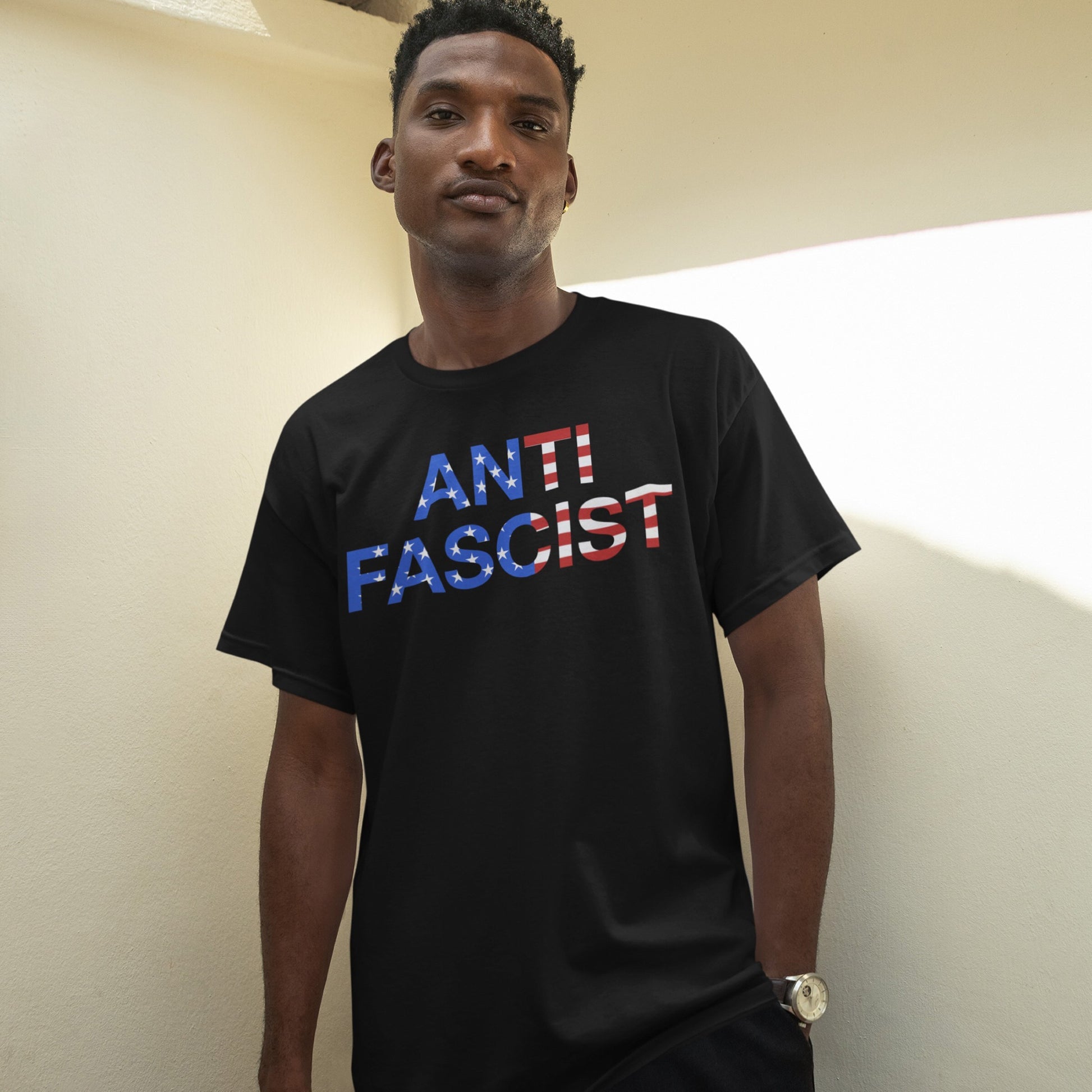 A young man models the Anti-Fascist USA Classic T-shirt featuring bold ANTI FASCIST text with an American-flag motif, embodying a message of equity and justice.