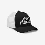 Anti Fascist Hat features a black front with ANTI FASCIST embroidered, complemented by white mesh back panels. Ethically made, unisex, and stylish, it supports the ACLU's mission.