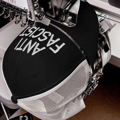 The Anti-Fascist Hat on an embroidery machine, displaying ANTI FASCIST in bold letters, represents a statement piece with a soft fit, ethically crafted for daily protest wear.