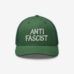 Green mesh-back trucker cap with a solid front panel, featuring ANTI FASCIST in bold white embroidery, symbolizing resistance and ethical production. A unisex statement piece supporting ACLU's mission for justice.
