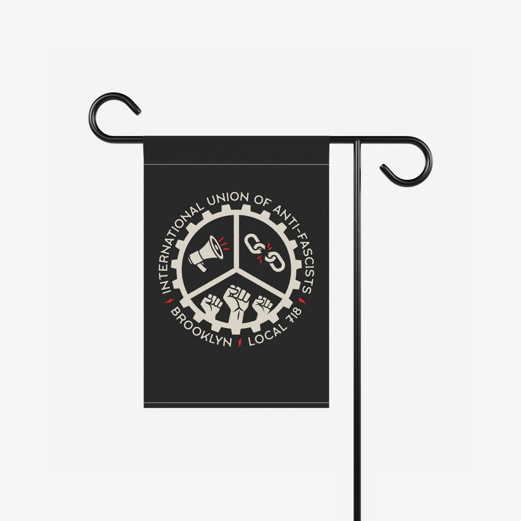 Brooklyn Anti-Fascist Union Garden Flag featuring a gear-toothed emblem with a megaphone, broken chains, and clenched fists, mounted on a metal stand, symbolizing protest and resistance.