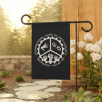 Brooklyn Anti-Fascist Union Garden Flag on a black metal stand in a garden. Featuring a gear-toothed logo with megaphone, broken chain, and raised fists, spotlighting anti-fascist pride.