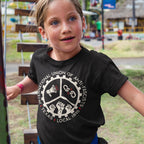 Young girl in a Texas Anti-Fascist Union T-shirt, depicting a gear-like logo with icons, climbing on an outdoor structure, symbolizing activism against fascism and support for equality.