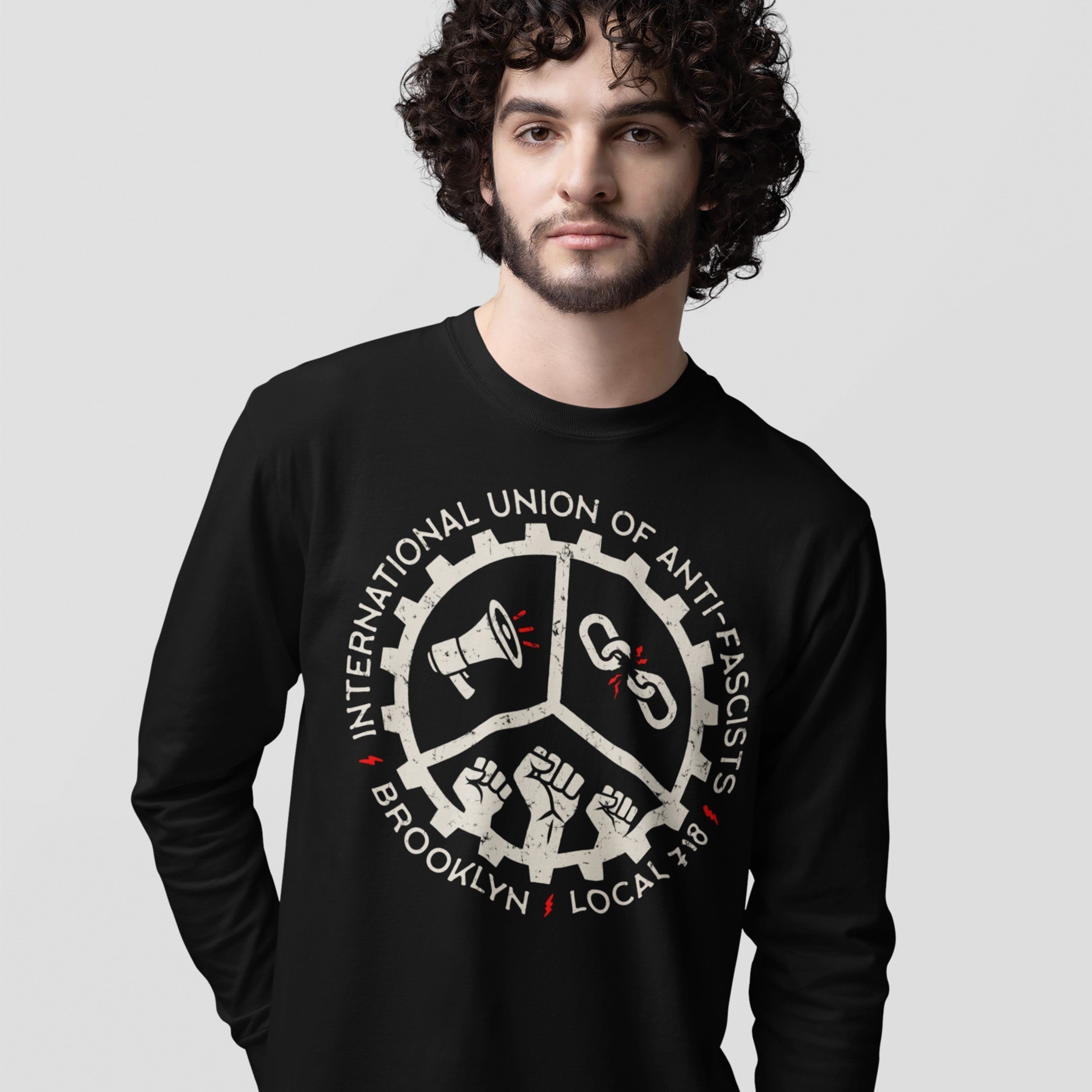 Brooklyn Anti-Fascist Union T-shirt features a black long-sleeve design with a union-style emblem of a megaphone, broken chains, and raised fists, symbolizing anti-fascist solidarity and Brooklyn pride.