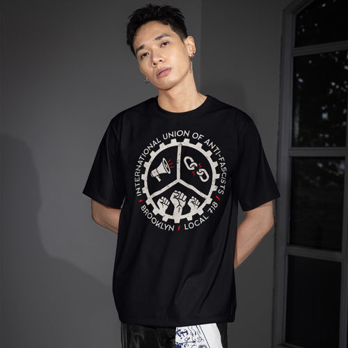 Young man wears a Brooklyn Anti-Fascist Union T-shirt, featuring a union-style graphic with a megaphone, broken chains, and raised fists. Perfect for those embracing borough pride and solidarity.