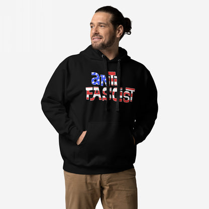 Man wearing Anti-Fascist USA Hoodie, featuring a ANTI FASCIST slogan in star-and-stripe design, hands in front pocket, paired with tan pants. Highlights patriotic resistance and activism.
