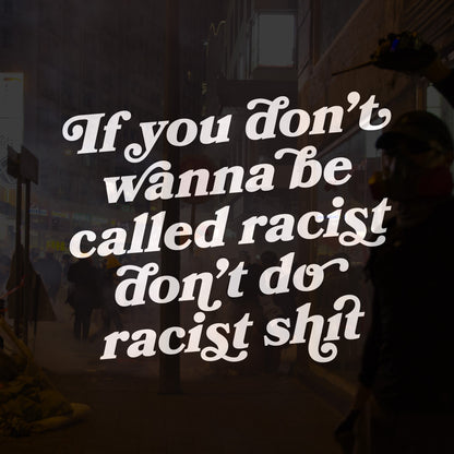 Anti-Racist Shirt with bold message overlay: “If you don’t wanna be called racist, don’t do racist shit,” set against a smoky street scene with people in protest gear, embodying activism and equality.