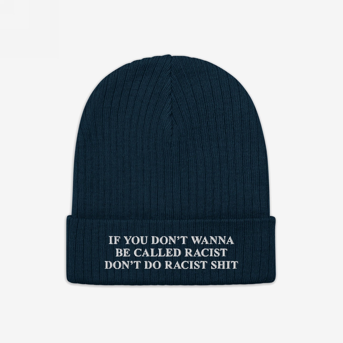 Anti-Racist Hat: A dark blue, rib-knit beanie with a folded cuff, featuring a bold white slogan challenging racism, embodying a statement of truth and action against discrimination.