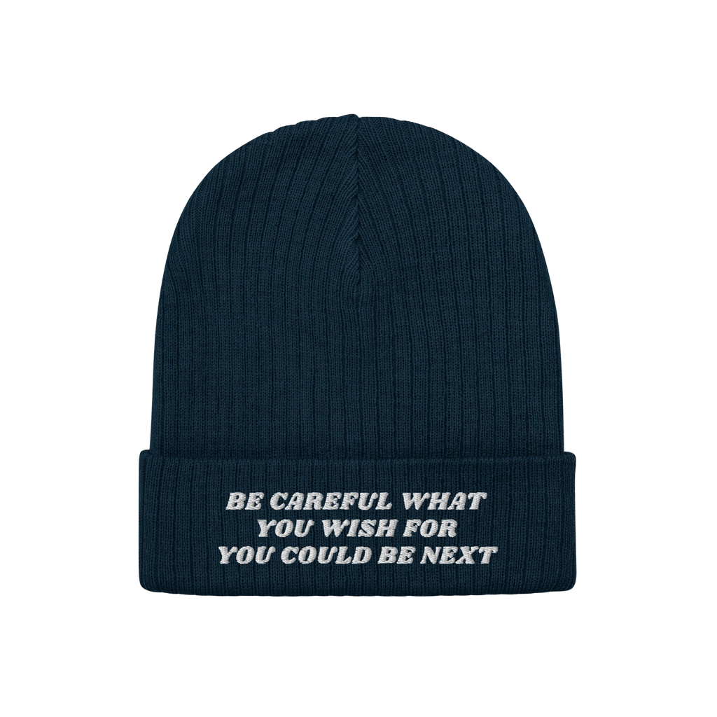 Anti-Racist Hat: A dark blue, rib-knit beanie with a folded cuff, featuring a bold white slogan challenging racism, embodying