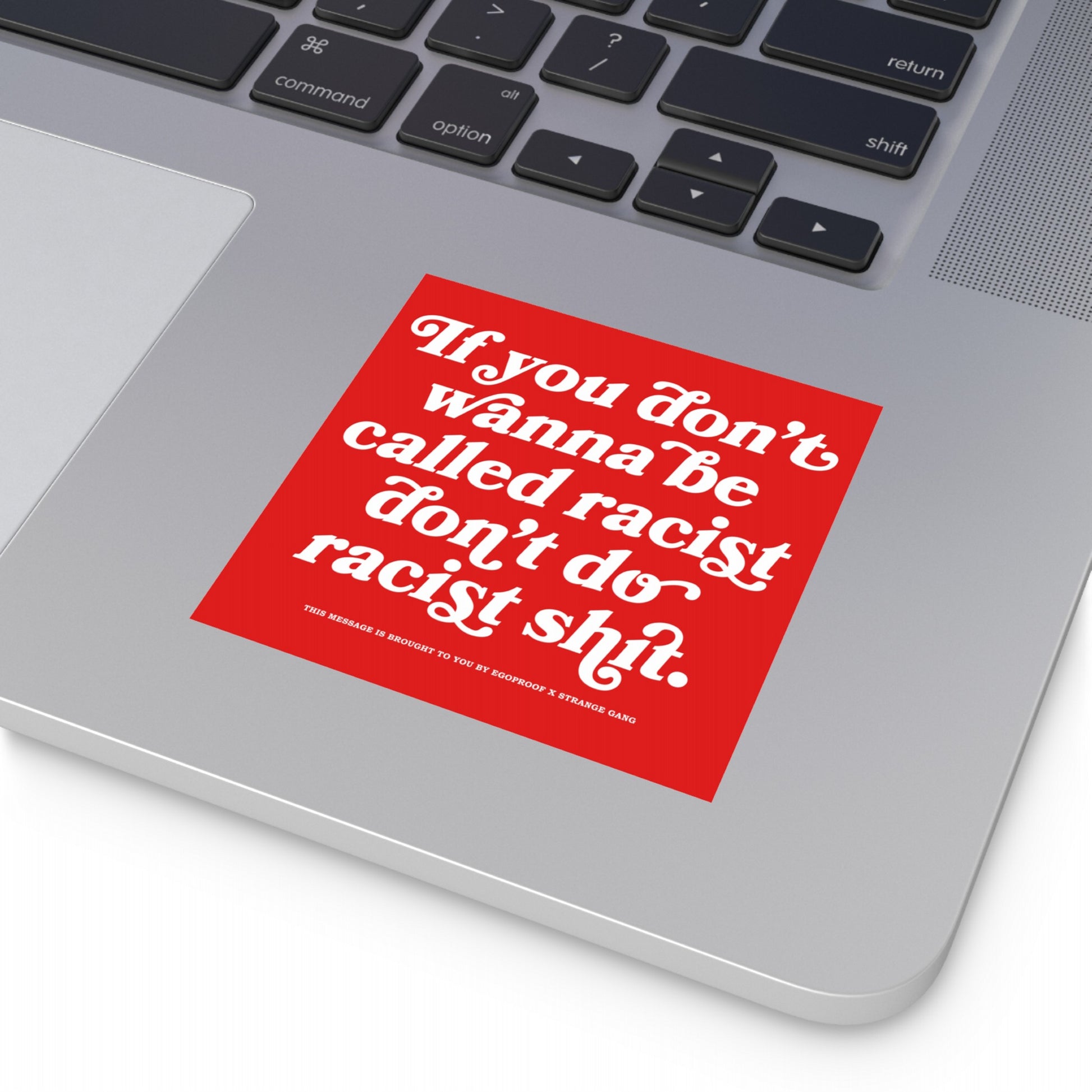 Silver laptop showcasing the Anti-Racist Sticker & Magnet with bold text: “If you don’t wanna be called racist don’t do racist shit.” Positioned below the keyboard, it represents a clear stance against racism.
