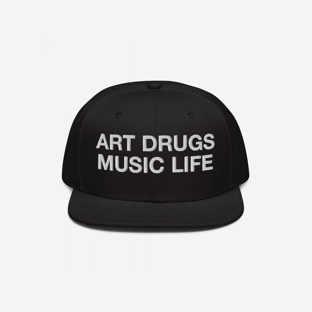 Black snapback cap with flat brim featuring “ART DRUGS MUSIC LIFE” in bold white embroidery, embodying creative expression and chaos. Perfect for those who embrace art, music, and an unapologetic lifestyle.