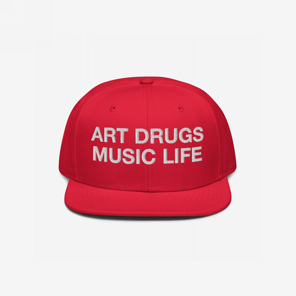 Bright red snapback hat with white text: ART DRUGS MUSIC LIFE, capturing a bold artistic manifesto for creativity and chaos enthusiasts. Ideal for artistic expression and unapologetic lifestyles.