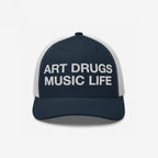 Art Drugs Music Life Hat: Navy trucker cap with bold white embroidery. Front reads “ART DRUGS MUSIC LIFE” in block letters, ideal for creative spirits embracing expression and experience. White mesh back adds comfort.