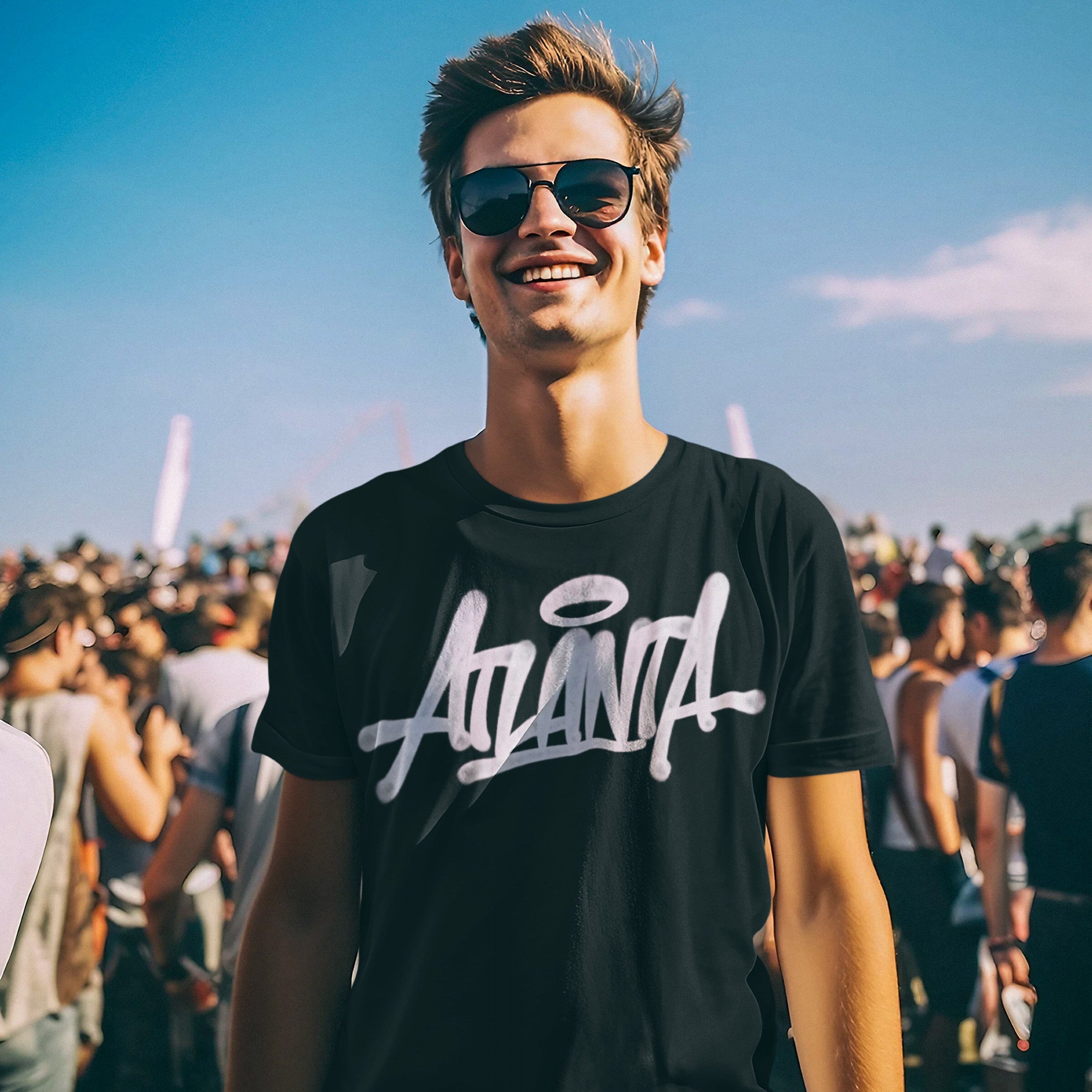 Young man at a festival wearing the Atlanta Handstyle T-shirt, featuring a bold graffiti-inspired Atlanta logo, embodying city pride and street art culture.