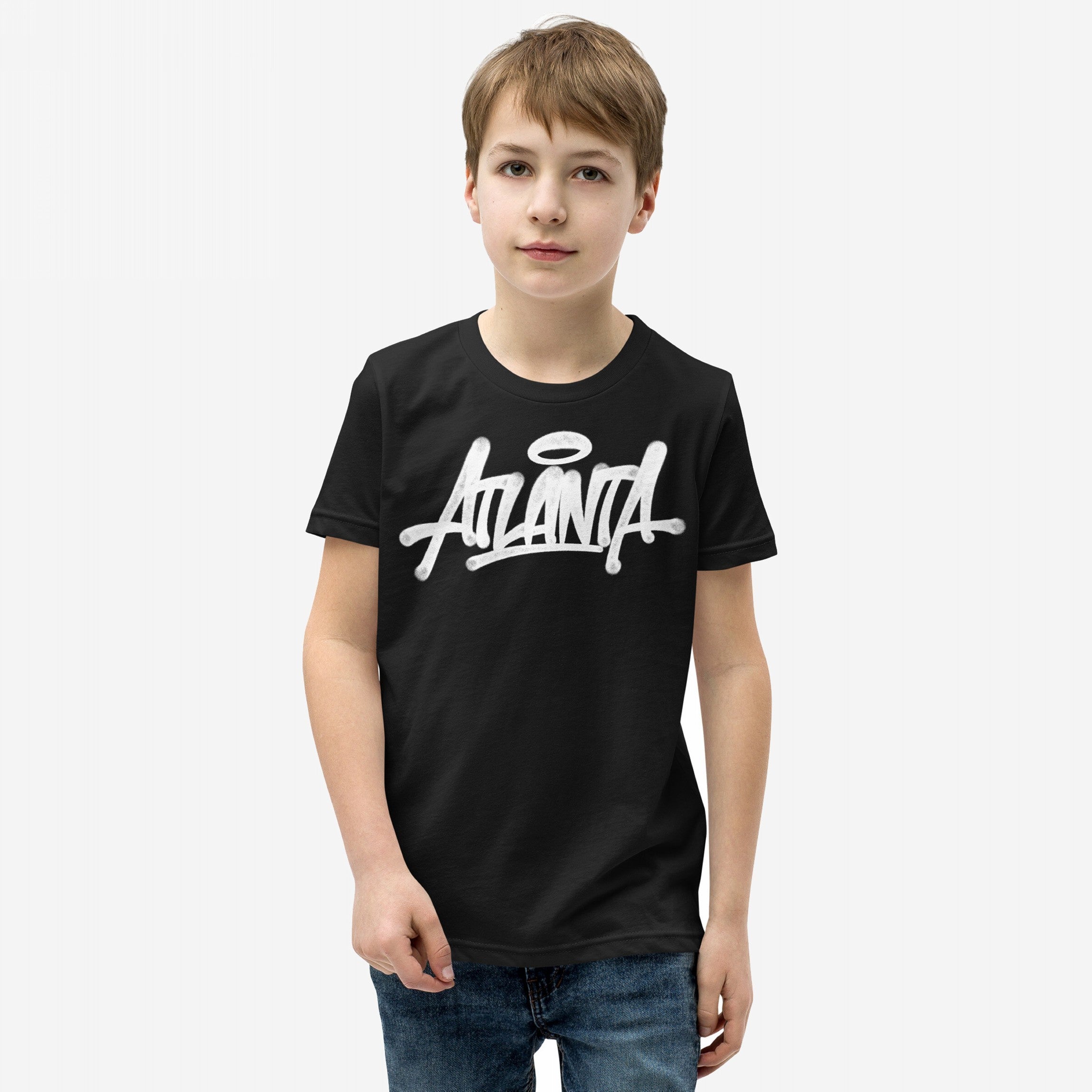 Young boy wearing the Atlanta Handstyle T-shirt, featuring bold graffiti-style Atlanta print, embodying street art culture and city pride, paired with blue jeans. Ideal for expressing Atlanta's creative spirit.